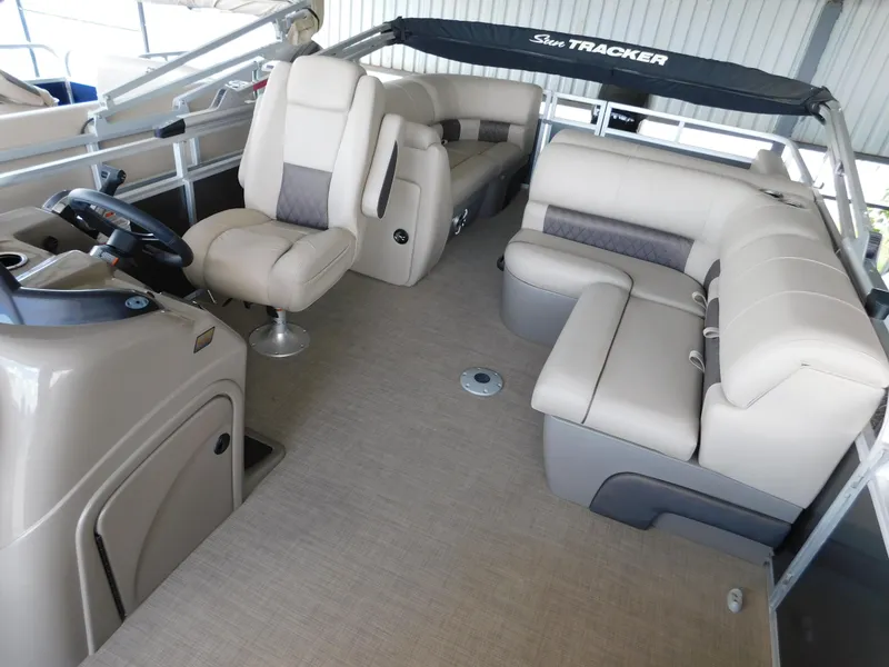 Slide: The Image of 2023 Sun Tracker Party Barge 22 RF DLX interior with beige seating and steering console. - 4