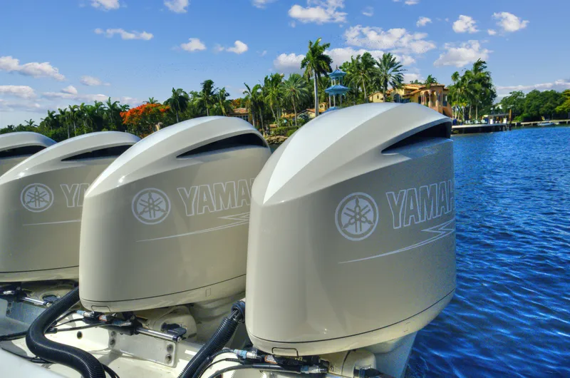 Slide: The Image of Three Yamaha outboard motors on a 2018 HCB 53 Sueños boat by a tropical waterfront. - 6