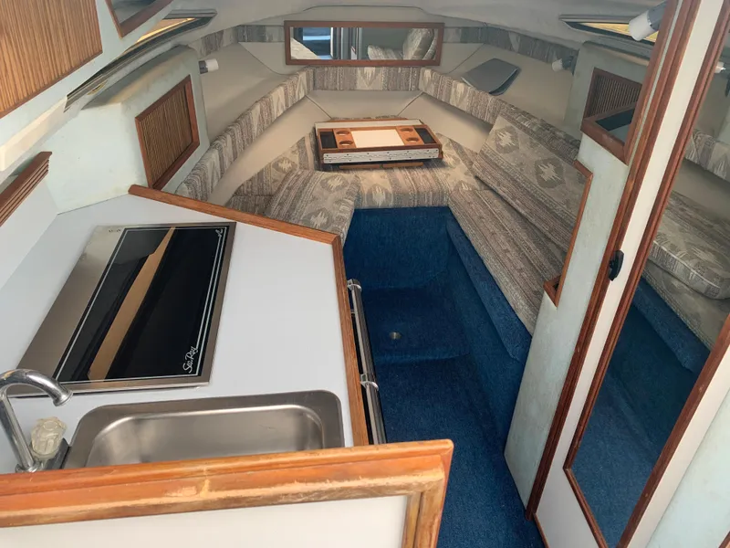 Slide: The Image of 1989 Sea Ray 230 Weekender cabin interior with kitchenette and seating area. - 11