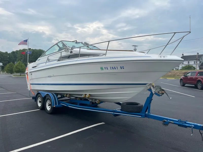 Slide: The Image of 1989 Sea Ray 230 Weekender boat on a blue trailer in a parking lot. - 2
