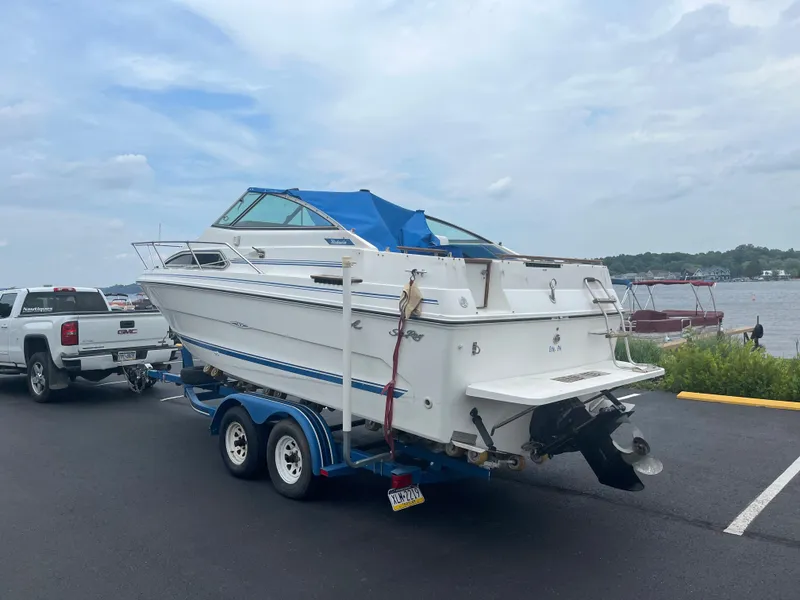 Slide: The Image of 1989 Sea Ray 230 Weekender boat on a trailer near a lake. - 4