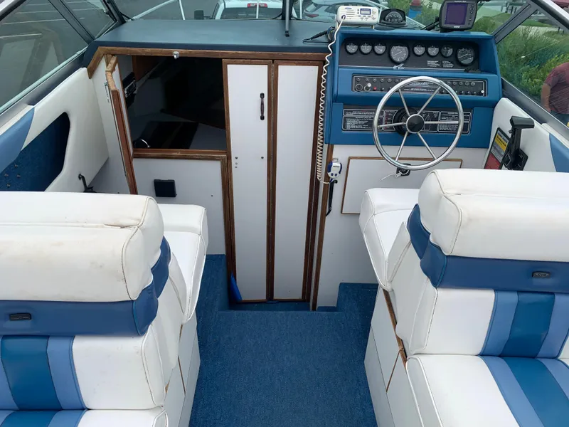 Slide: The Image of 1989 Sea Ray 230 Weekender boat interior with blue and white seating and control panel. - 7