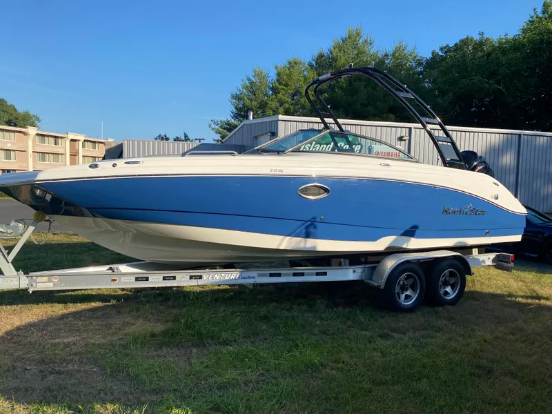 Slide: The Image of 2023 NauticStar 243DC Sport Deck boat on a trailer, side view. - 6