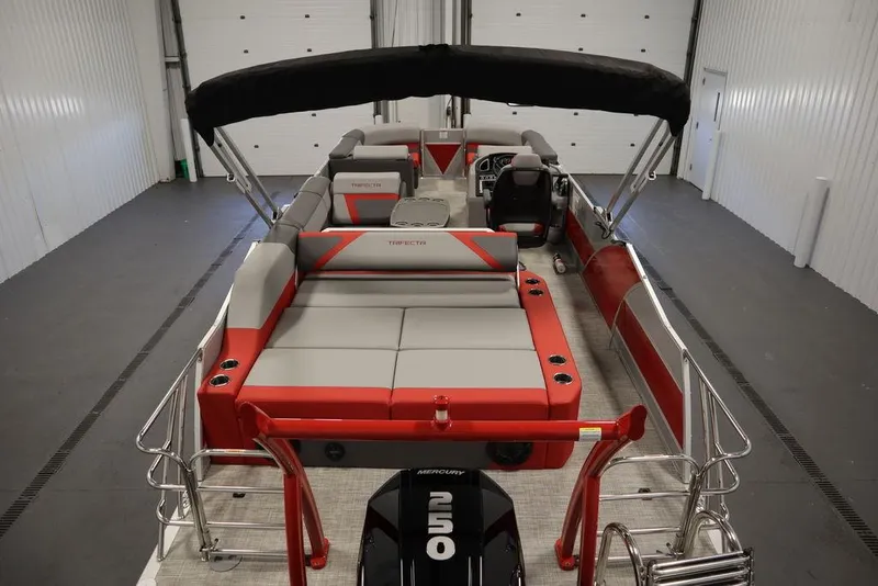 Slide: The Image of 2023 Trifecta 23SB2 SS 3.0 pontoon boat with red and gray interior in a storage facility. - 10