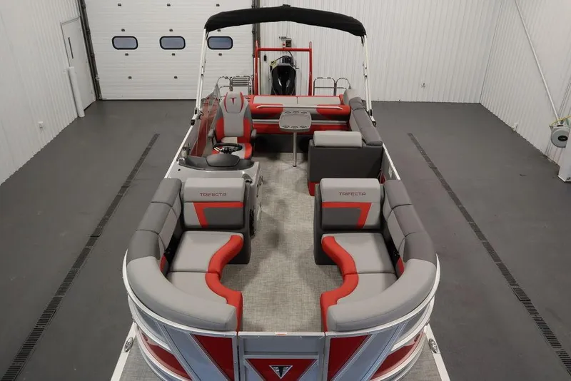 Slide: The Image of 2023 Trifecta 23SB2 SS 3.0 pontoon boat with red and gray seating in a showroom. - 25
