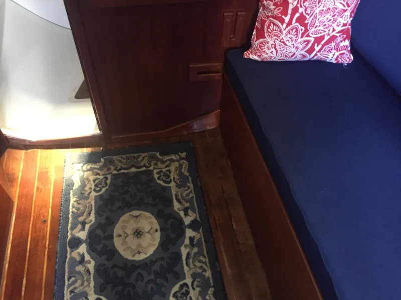 Slide: The Image of Interior of 1980 Tartan 33 sailboat with wooden floor, blue sofa, and decorative rug. - 19