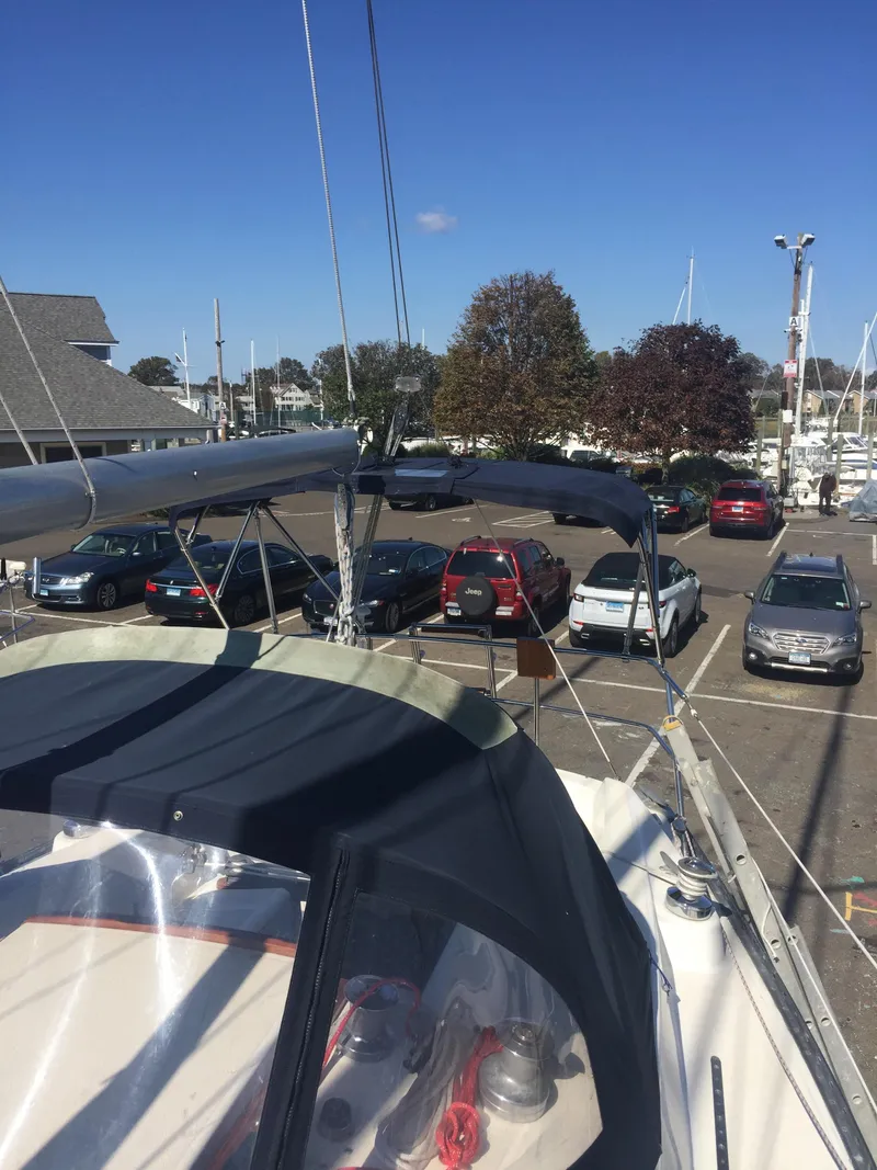 Slide: The Image of 1980 Tartan 33 sailboat docked at marina with cars in the background. - 6