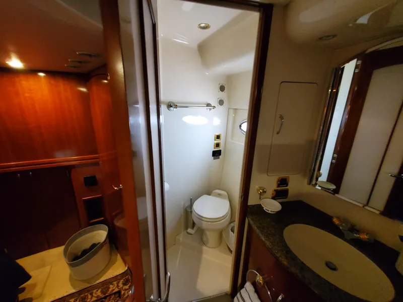 Slide: The Image of 2003 Carver 570 Voyager Pilothouse bathroom with toilet, sink, and wooden cabinetry. - 45