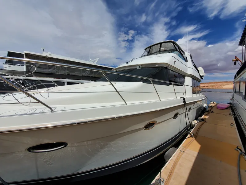 Slide: The Image of 2003 Carver 570 Voyager Pilothouse yacht docked under a partly cloudy sky. - 5