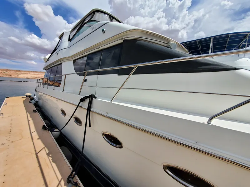Slide: The Image of 2003 Carver 570 Voyager Pilothouse yacht docked at a marina under a partly cloudy sky. - 7