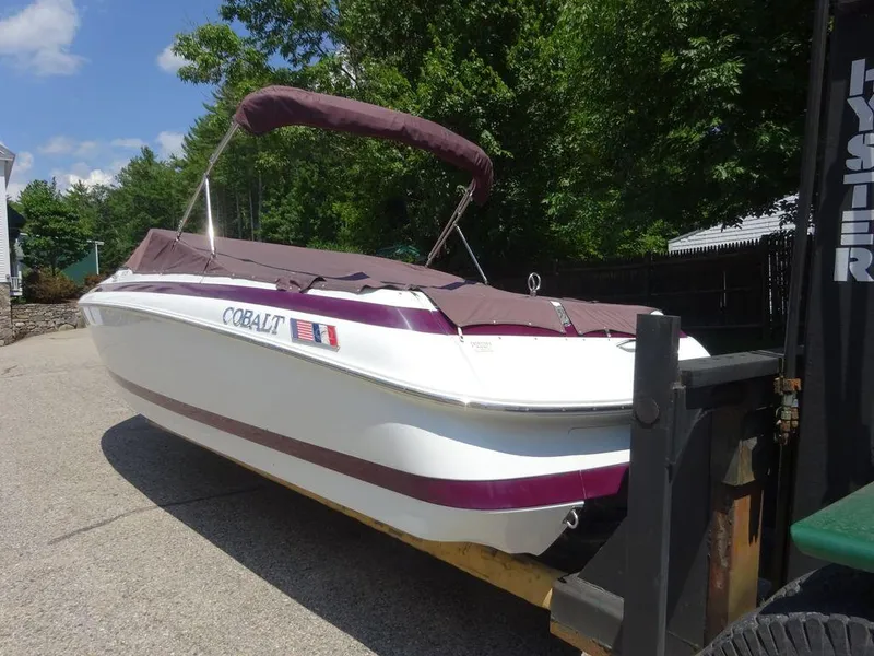 Slide: The Image of 1999 Cobalt 253 boat with maroon cover on trailer, parked outdoors. - 4