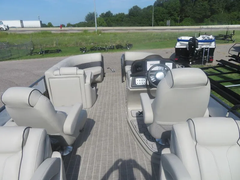 Slide: The Image of 2020 Xcursion 245 Sport Toon boat interior with beige seating and steering console. - 2