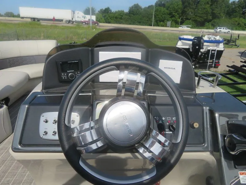 Slide: The Image of 2020 Xcursion 245 Sport Toon boat dashboard with steering wheel and controls. - 3