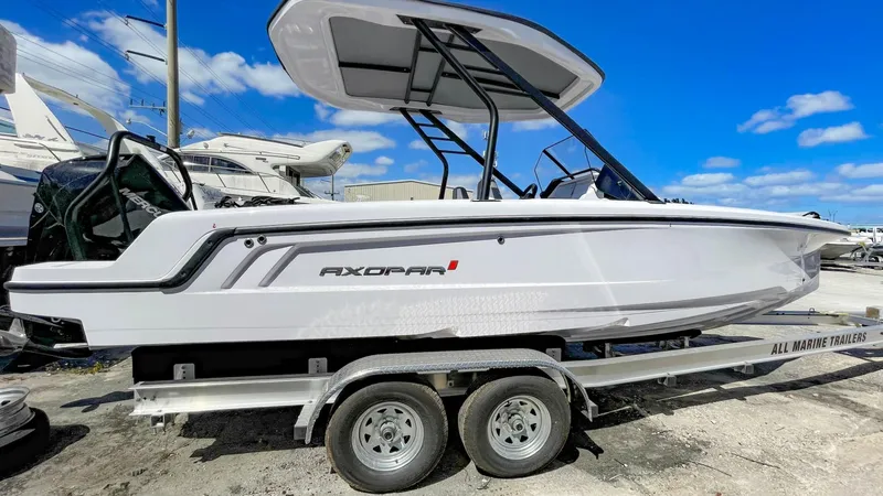 Slide: The Image of 2023 Axopar 22 T-Top boat on a trailer under a clear blue sky. - 0