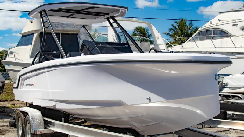 Slide: The Image of 2023 Axopar 22 T-Top boat on a trailer, docked at a marina. - 1