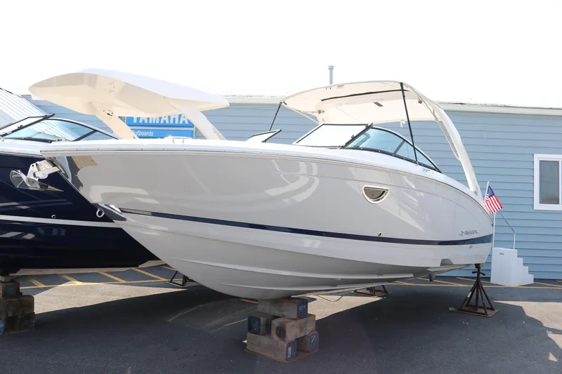 Slide: The Image of 2023 Regal LS6 boat displayed outdoors, white hull, sleek design, American flag, parked on blocks. - 1