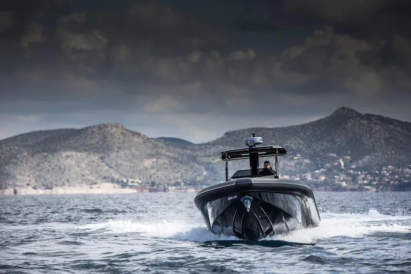 Slide: The Image of 2024 Skipper-BSK 38NC boat cruising on open water with mountainous background. - 7