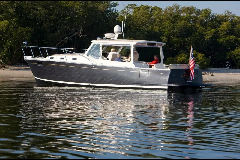 Slide: The Image of 2023 MJM 40z boat cruising near a shoreline with trees in the background. - 0