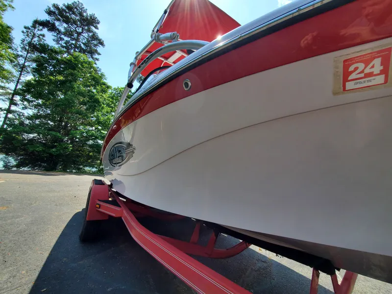 Slide: The Image of 2005 Correct Craft SV-211 Limited boat on trailer, red and white design, parked near trees. - 11