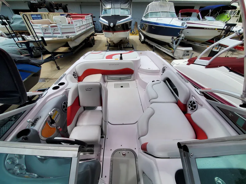 Slide: The Image of 2005 Correct Craft SV-211 Limited boat interior with white and red seating, docked among other boats. - 20
