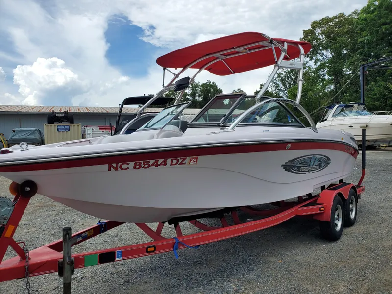 Slide: The Image of 2005 Correct Craft SV-211 Limited boat on trailer with red canopy in outdoor setting. - 3