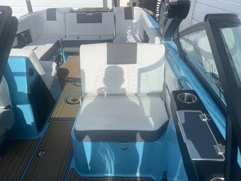 Slide: The Image of 2022 MasterCraft X26 boat interior with white and gray seating, blue accents, and cup holders. - 8