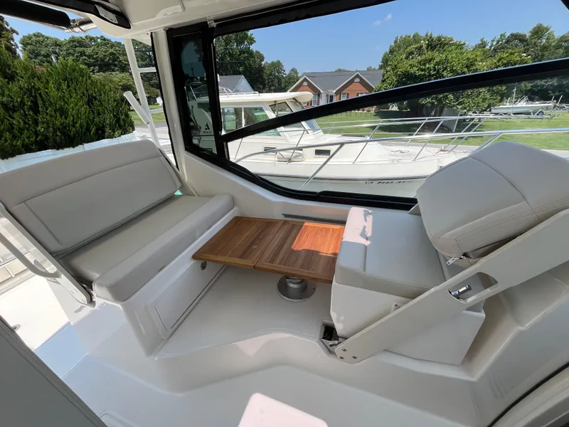 Slide: The Image of 2025 Boston Whaler 325 Conquest interior with seating and wooden table, showcasing luxury design. - 19