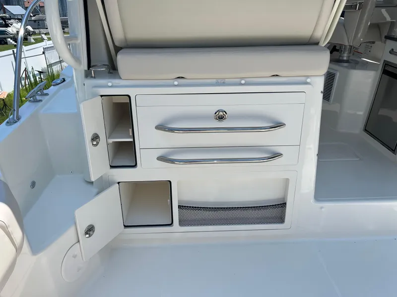 Slide: The Image of 2025 Boston Whaler 325 Conquest interior storage compartments with open doors and drawers. - 31