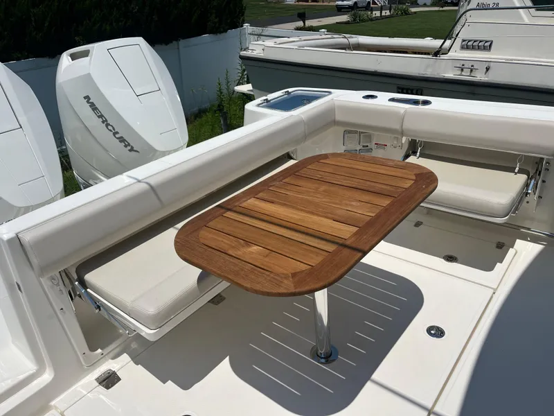 Slide: The Image of 2025 Boston Whaler 325 Conquest boat interior with wooden table and Mercury engines. - 38