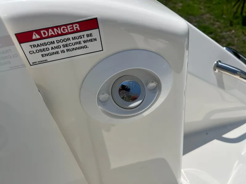 Slide: The Image of 2025 Boston Whaler 325 Conquest transom door warning label and latch detail. - 42