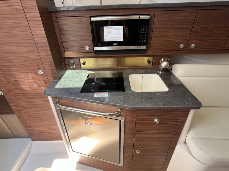 Slide: The Image of 2025 Boston Whaler 325 Conquest galley with microwave, sink, and cooktop. - 8