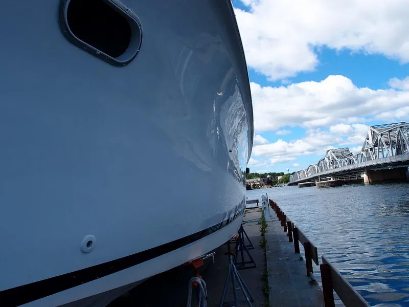 Slide: The Image of 1961 Hatteras Convertible yacht docked near a bridge on a sunny day. - 4