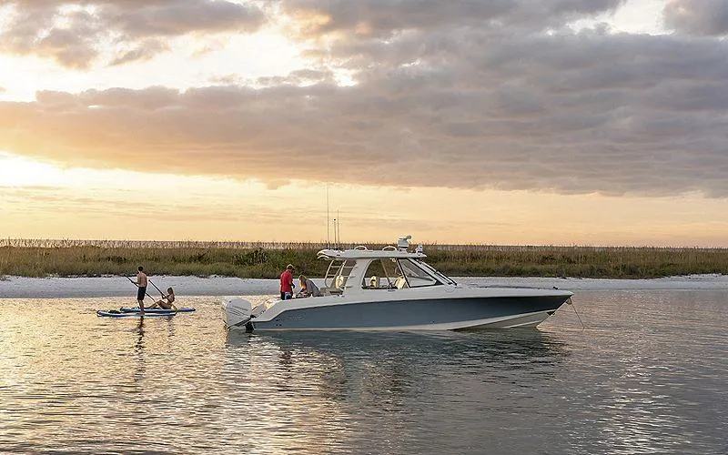 Slide: The Image of 2024 Boston Whaler 380 Realm boat on calm water at sunset. - 2