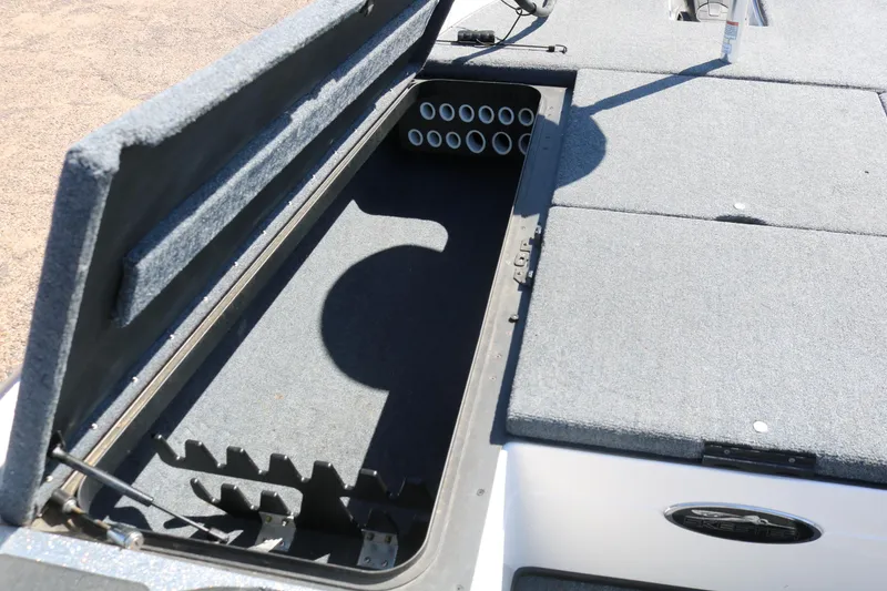 Slide: The Image of 2009 Skeeter 20i boat storage compartment with rod holders and carpeted interior. - 9