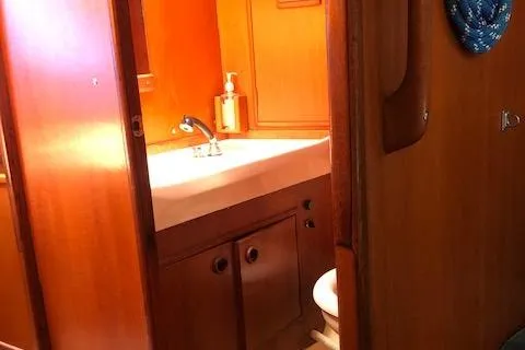 Slide: The Image of Interior of 1981 Nautor Swan 371 Sloop, featuring a compact wooden bathroom with sink and toilet. - 16