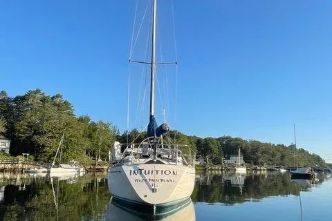 Slide: The Image of 1981 Nautor Swan 371 Sloop sailboat docked on calm water, surrounded by trees. - 46