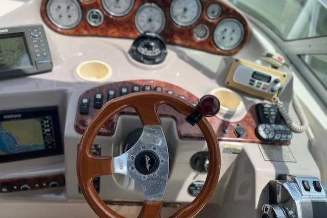 Slide: The Image of 2004 Rinker 342 Express Cruiser dashboard with wood steering wheel and navigation instruments. - 18