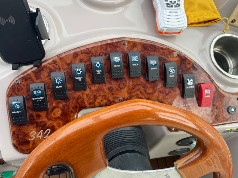 Slide: The Image of Control panel of a 2004 Rinker 342 Express Cruiser with various switches and a wooden steering wheel. - 19