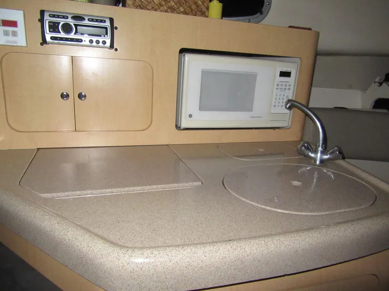 Slide: The Image of 2002 Boston Whaler 295 Conquest galley with microwave, sink, and storage cabinets. - 11