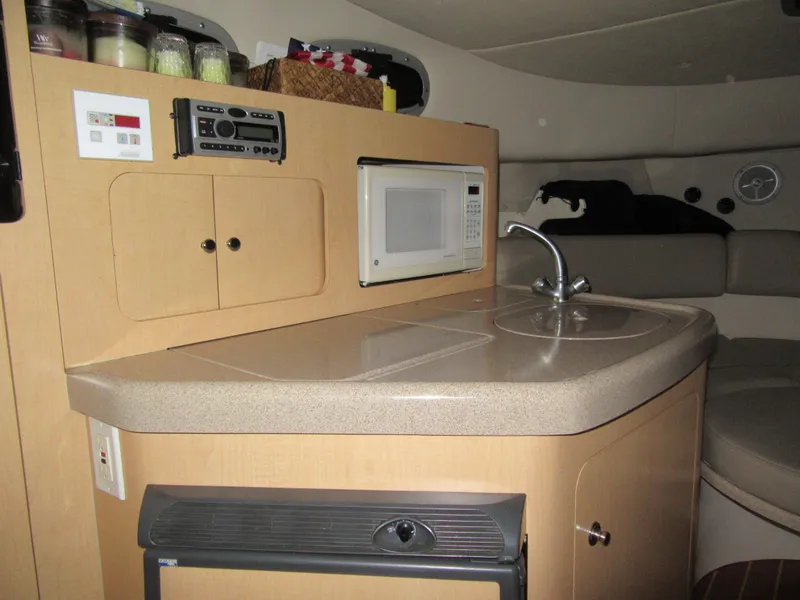 Slide: The Image of 2002 Boston Whaler 295 Conquest cabin kitchen with microwave, sink, and storage. - 5
