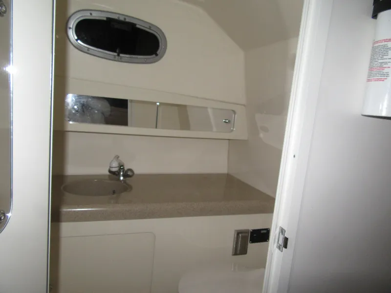 Slide: The Image of 2002 Boston Whaler 295 Conquest bathroom with sink, mirror, and porthole window. - 7
