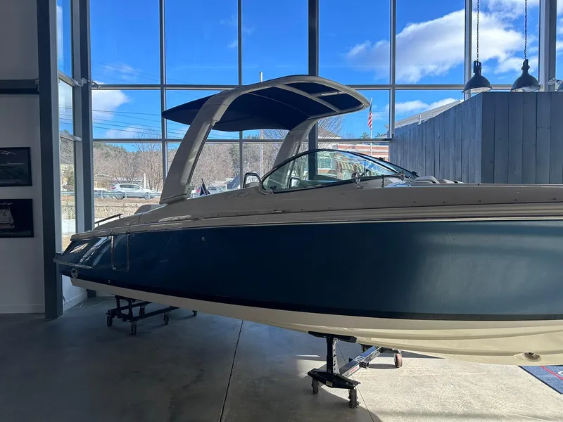 Slide: The Image of 2024 Chris-Craft Launch 28 GT boat displayed indoors with blue hull and canopy. - 2