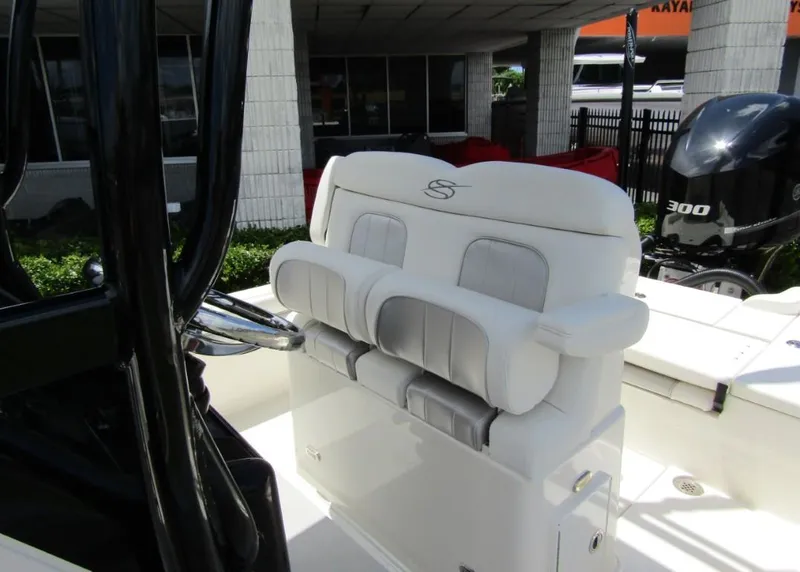 Slide: The Image of 2021 ShearWater 250 Carolina Bay boat with cushioned seating and steering wheel. - 13