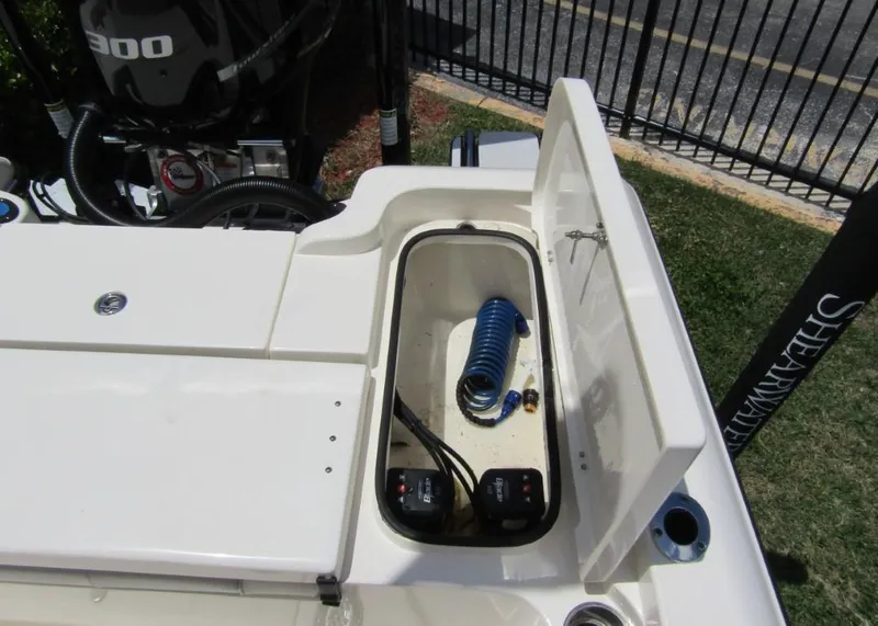 Slide: The Image of 2021 ShearWater 250 Carolina Bay storage compartment with coiled hose and engine controls. - 24