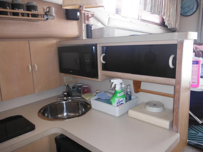 Slide: The Image of 1990 Silverton 34 Convertible boat kitchen with sink, microwave, and storage cabinets. - 15