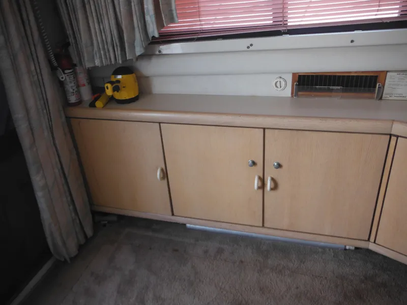 Slide: The Image of Interior of a 1990 Silverton 34 Convertible boat with wooden cabinets and a yellow flashlight. - 36