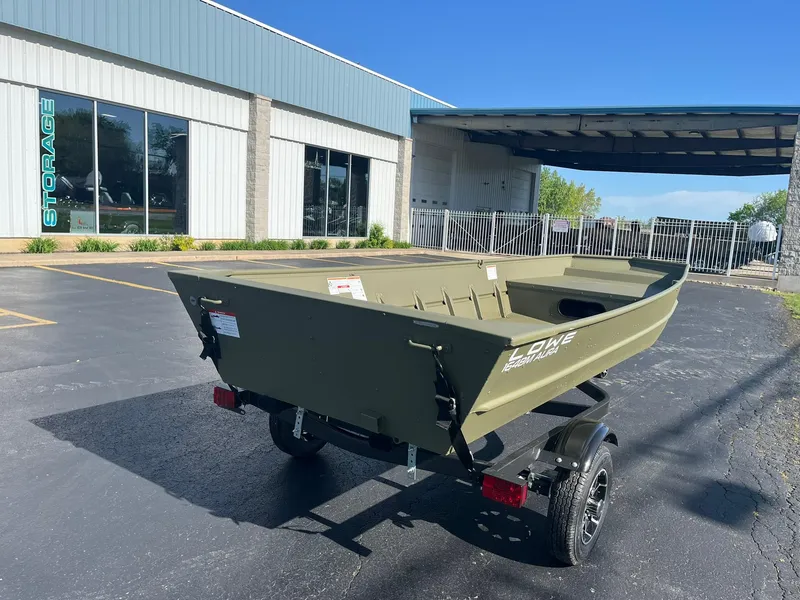 Slide: The Image of 2024 Lowe Jon L1648M Aura boat on trailer outside storage facility. - 2