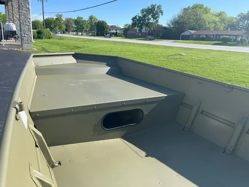 Slide: The Image of 2024 Lowe Jon L1648M Aura boat interior, green aluminum hull, parked outdoors. - 6