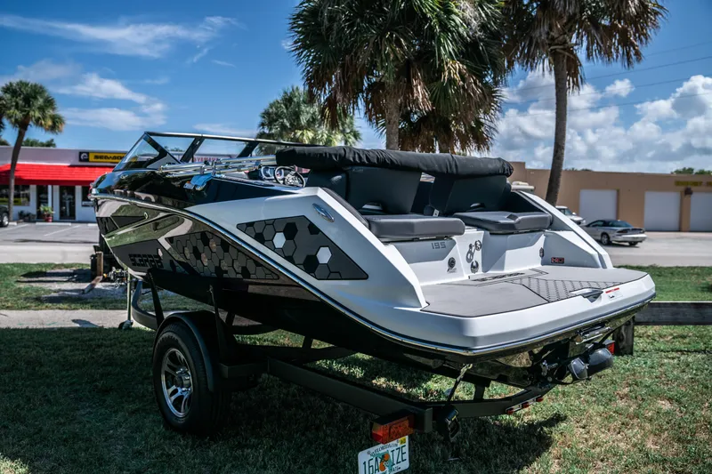 Slide: The Image of 2021 Scarab 195 boat on trailer, parked outdoors with palm trees in the background. - 5