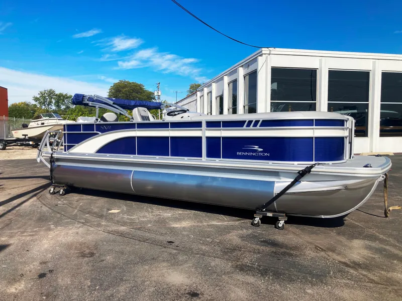 The Image of 2023 Bennington 22 SXSAPG pontoon boat with blue accents, parked outdoors. - 0